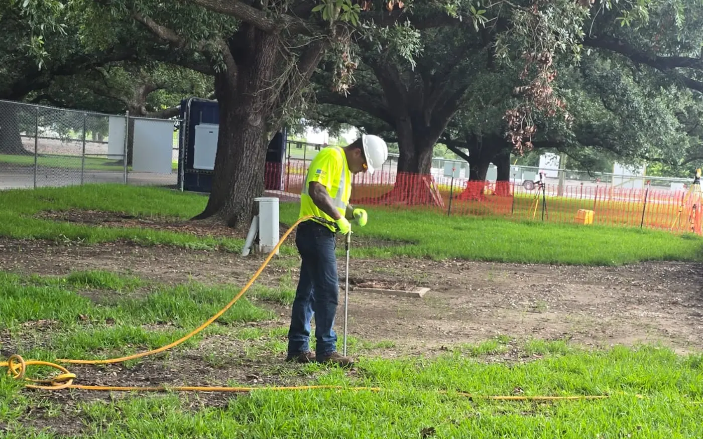 Veteran Tree Care crew member working the root zone of large oaks inside a fenced work zone